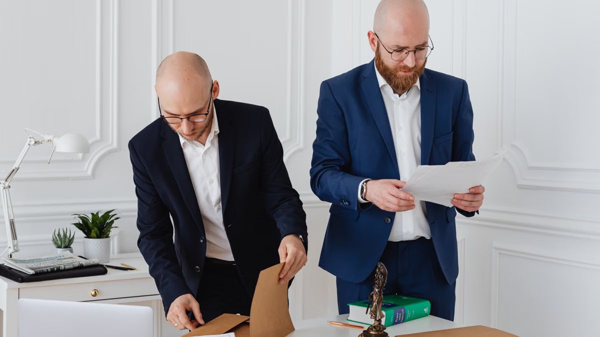 Two business professionals in corporate attire reviewing documents in a modern office setting.